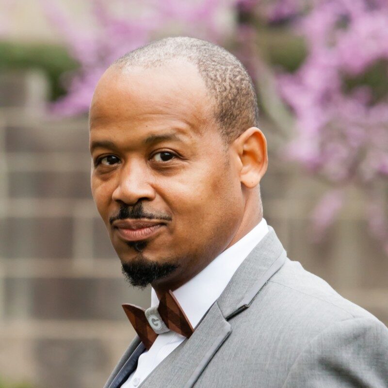 Professional man in a gray suit smiling outdoors.